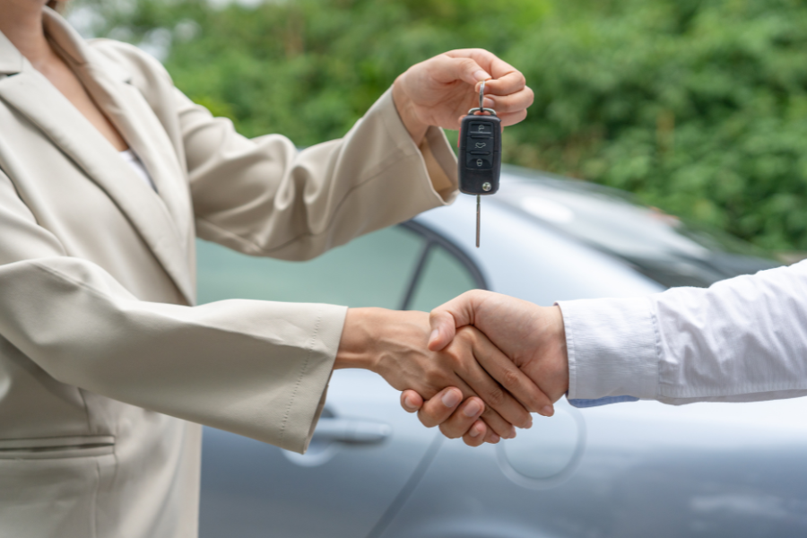 car dealer giving key to buyer of new car